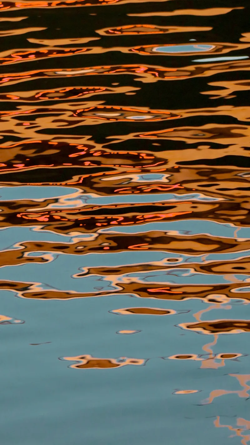 Warm light rippling across dark water in abstract reflections