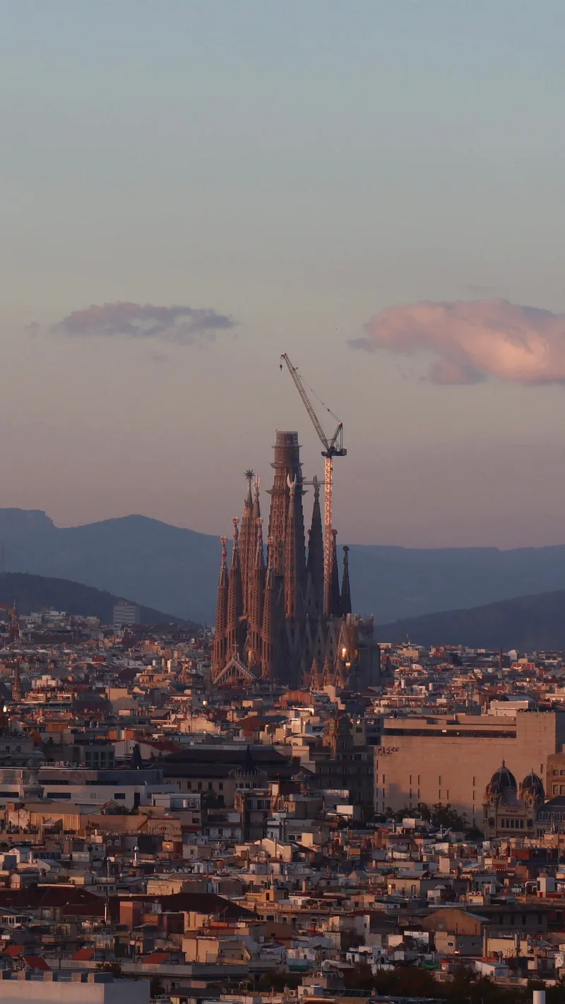 The Sagrada Família rising above the rooftops of Barcelona, with hills behind