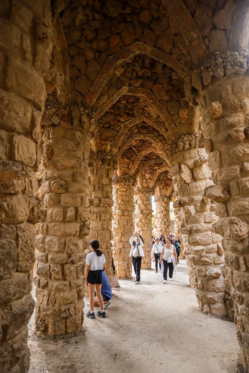 Visitors walking through the stone colonnade of Park Güell