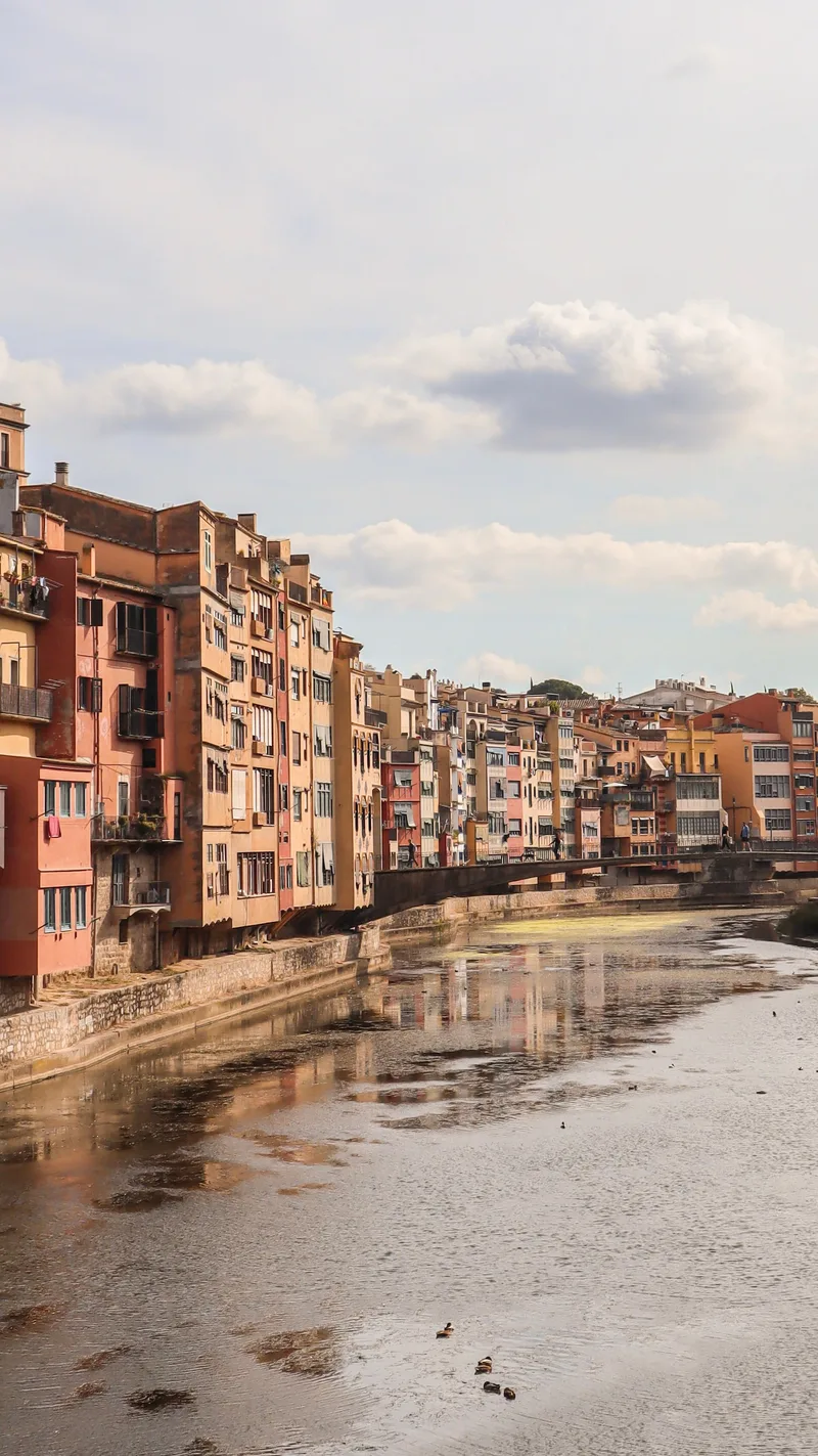 Colourful houses lining the River Onyar in Girona under a cloudy sky
