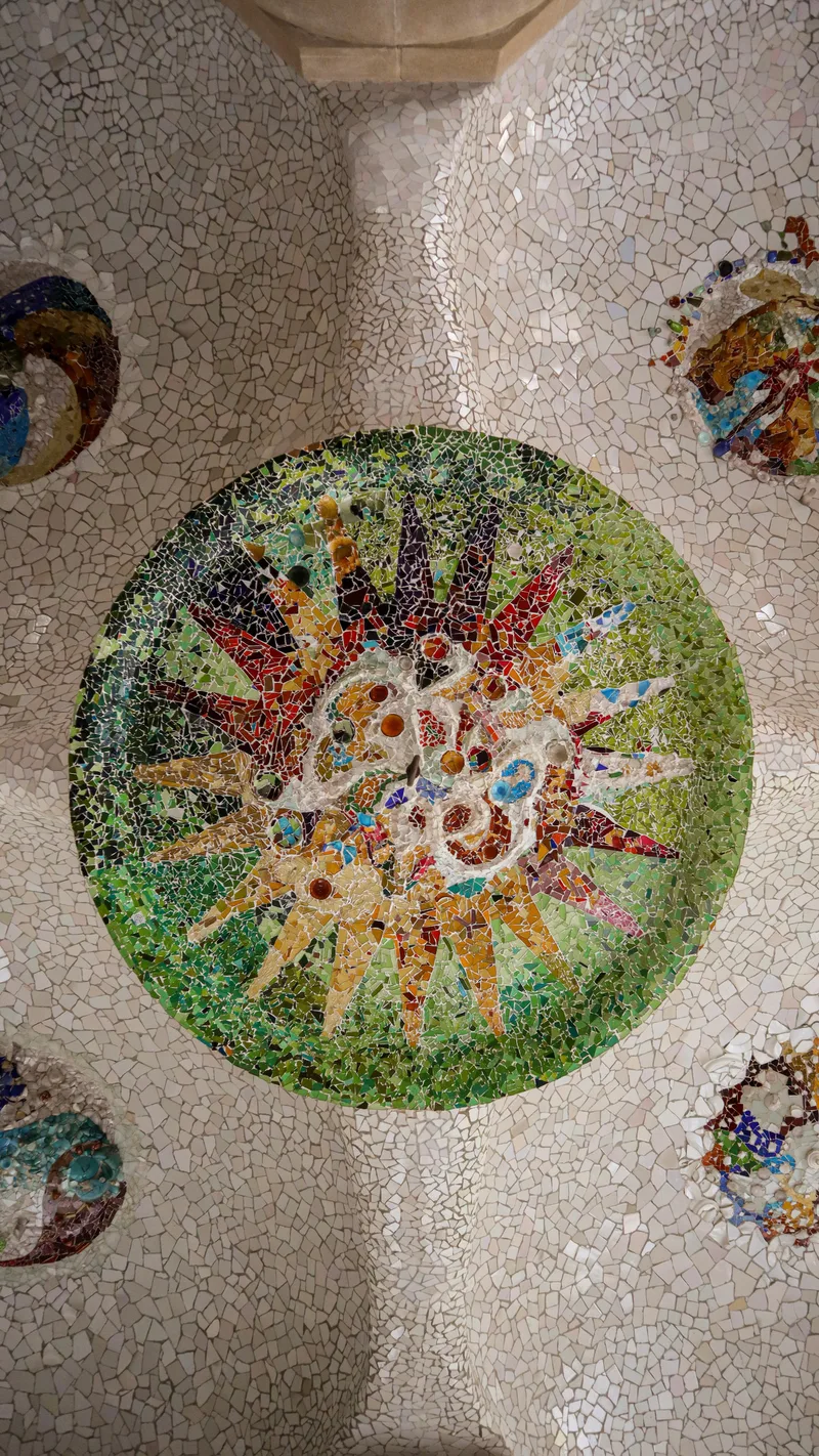 A circular mosaic medallion of broken tiles set into a white ceiling