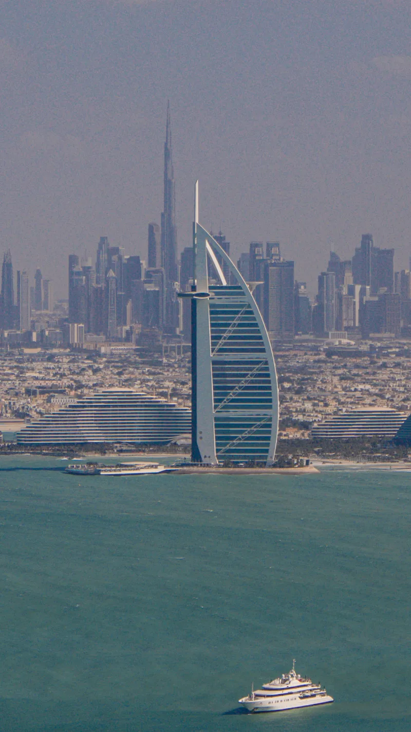 The sail-shaped Burj Al Arab in front of the Dubai skyline, with a yacht on turquoise water