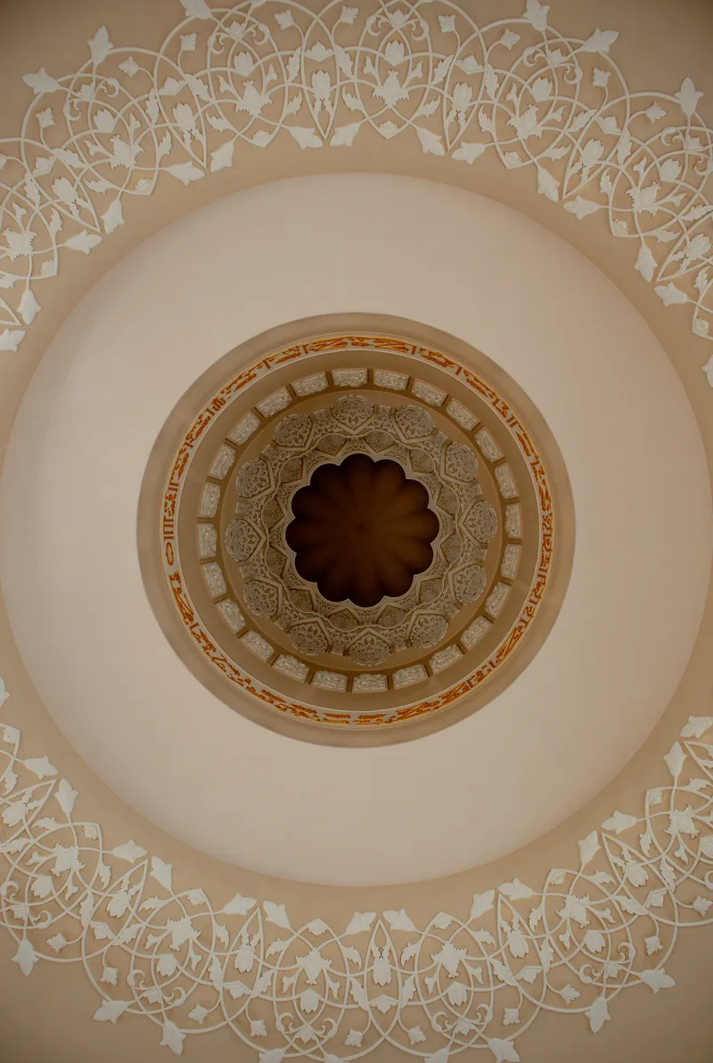 Ornate cream and gold pattern inside a mosque dome, seen from directly below