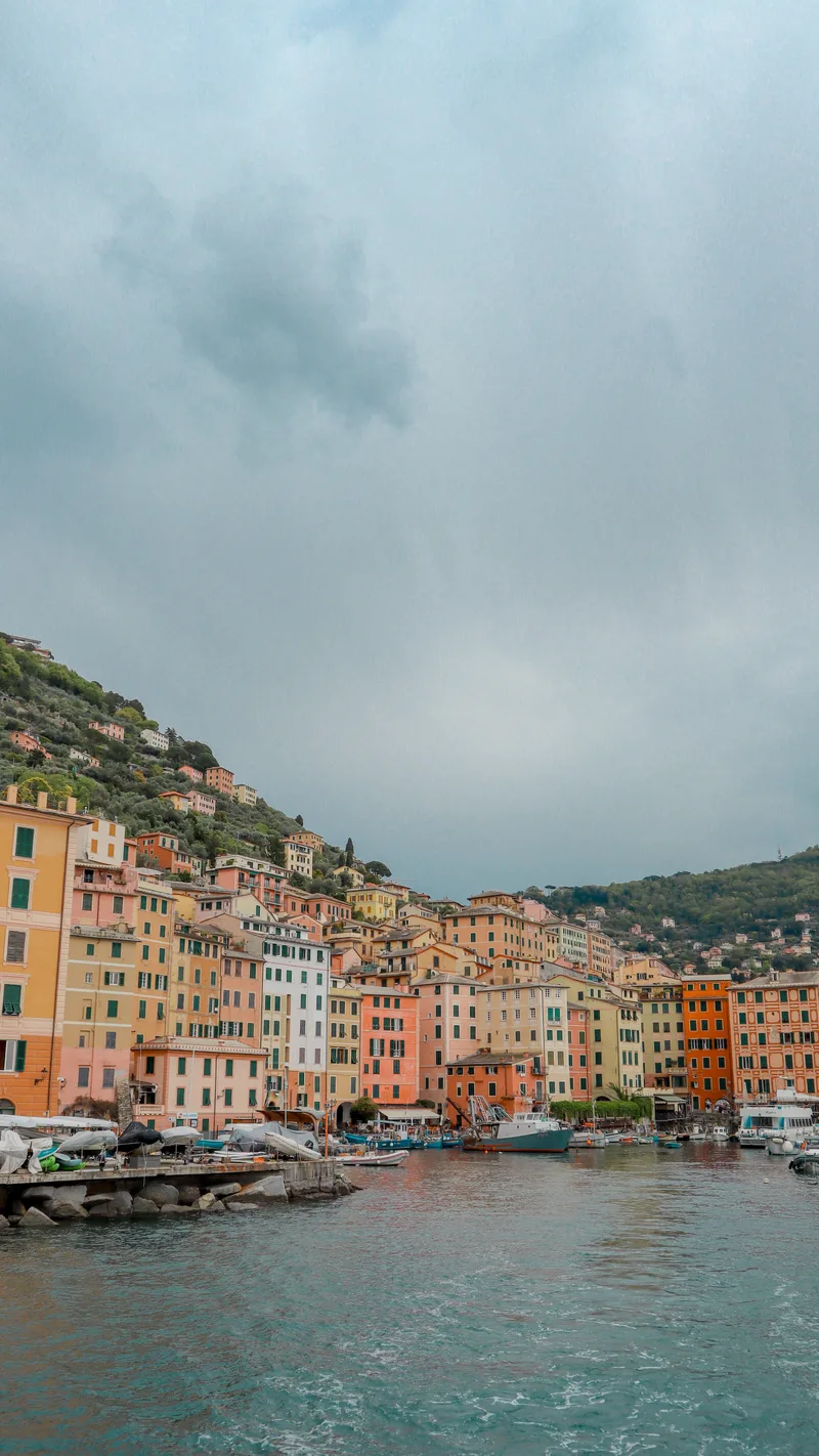Tall, colourful houses along the harbour at Camogli under storm clouds