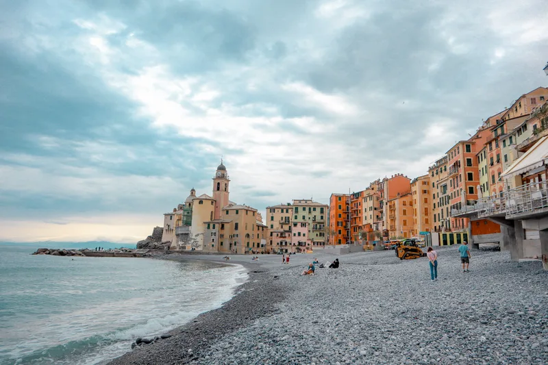 A pebble beach curving towards a church and pastel houses