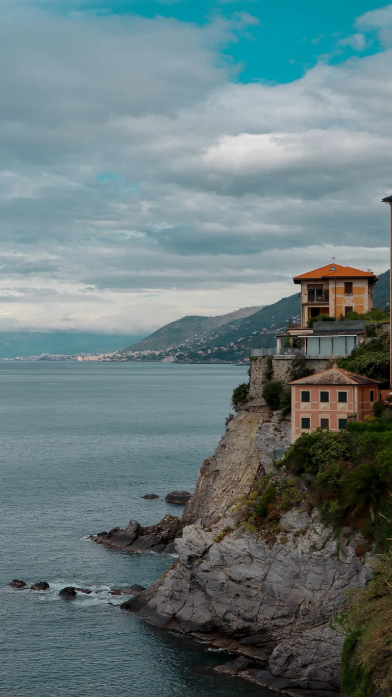 A house on a rocky cliff above the sea, with the coastline fading into the distance