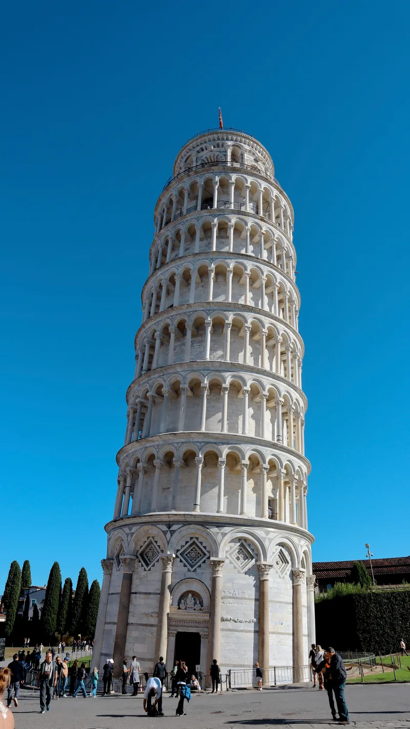 The Leaning Tower of Pisa against a deep blue sky with visitors below