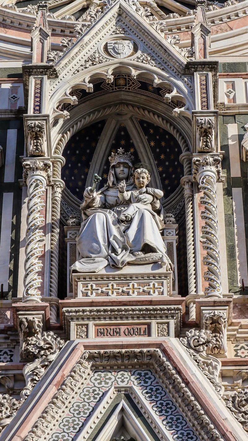 A marble statue of the Madonna and Child in a carved niche on the cathedral facade