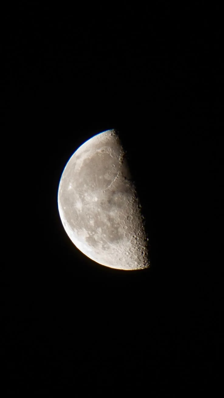 A half-lit moon against a black sky