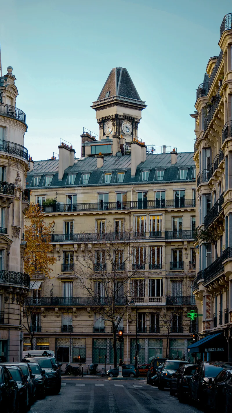 Haussmann apartment buildings and a clock tower at the end of a Paris street