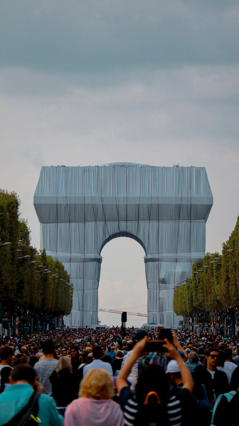 Crowds in front of the Arc de Triomphe wrapped in silver-blue fabric