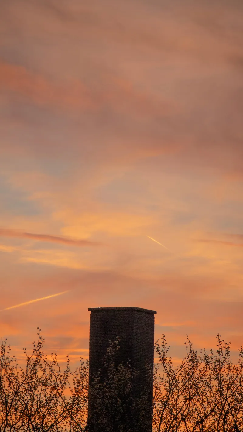 A chimney silhouetted against an orange sunset
