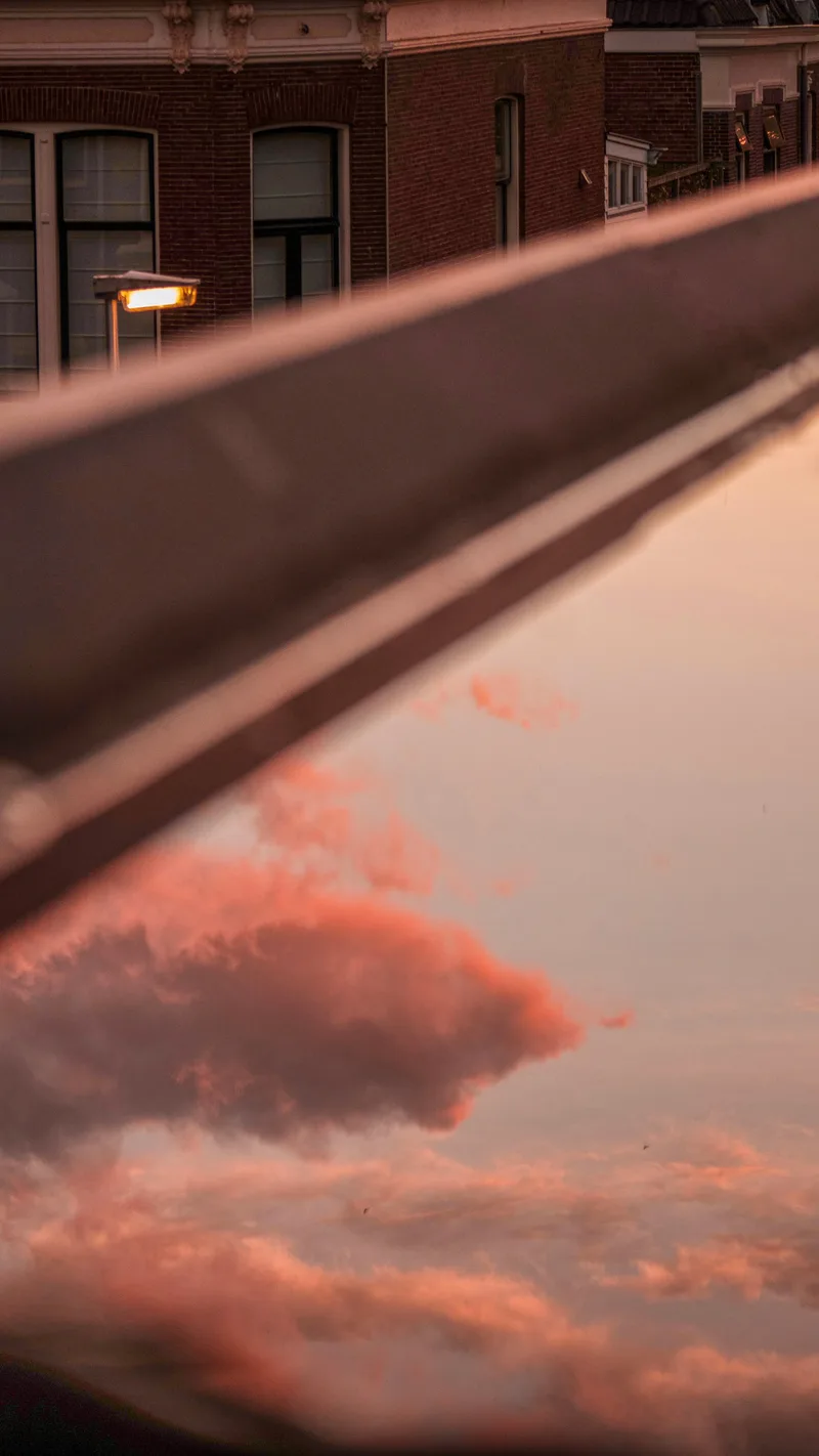 Pink clouds reflected in a window beside a brick building
