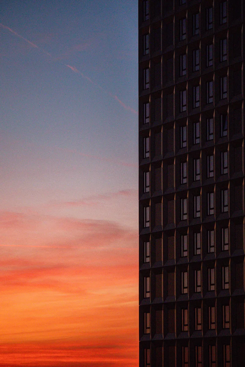 A dark high-rise beside a pink and orange evening sky
